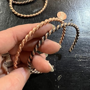 May include: Three twisted wire bracelets, one is copper and two are black and copper.