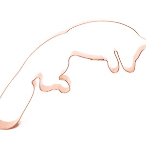 May include: A copper cookie cutter shaped like a jumping otter. The otter is in mid-air with its legs extended and its tail curled.