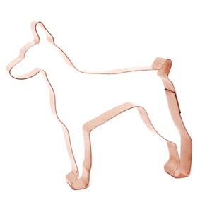 May include: Copper cookie cutter in the shape of a standing dog. The cutter is a light copper colour.