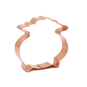 Könnte beinhalten: Kupferfarbener Ausstecher in Form eines Goldtopfes. Der Ausstecher hat einen wellenförmigen oberen Rand und einen abgerundeten Körper, perfekt für die Herstellung von Leckereien zum St. Patrick's Day. Das Metall hat einen warmen, glänzenden Ton vor weißem Hintergrund.