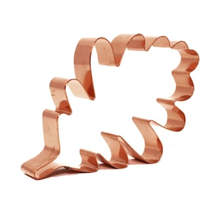 May include: A copper-coloured metal cookie cutter shaped like an oak leaf. The cutter has a detailed design with multiple layers.