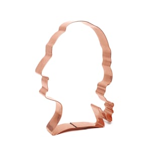May include: A copper cookie cutter shaped like a person's head with a wavy outline.