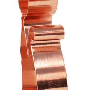 May include: A copper-colored cookie cutter shaped like a cat. The cutter is made of metal and has a smooth, polished finish.