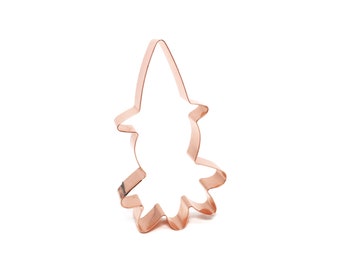 May include: A copper-colored cookie cutter shaped like a witch with a pointed hat and a flowing skirt.