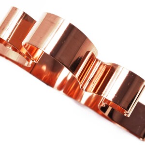 May include: A copper-colored cookie cutter shaped like a cloud with three rounded sections.