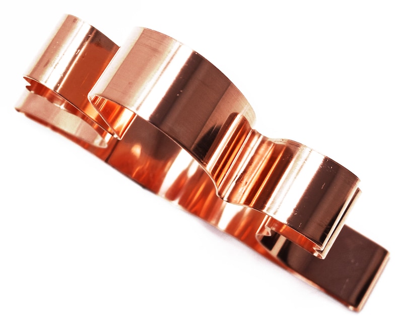 May include: A copper-colored cookie cutter shaped like a cloud with three rounded sections.