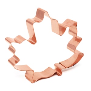 May include: A copper-colored metal cookie cutter shaped like a maple leaf.
