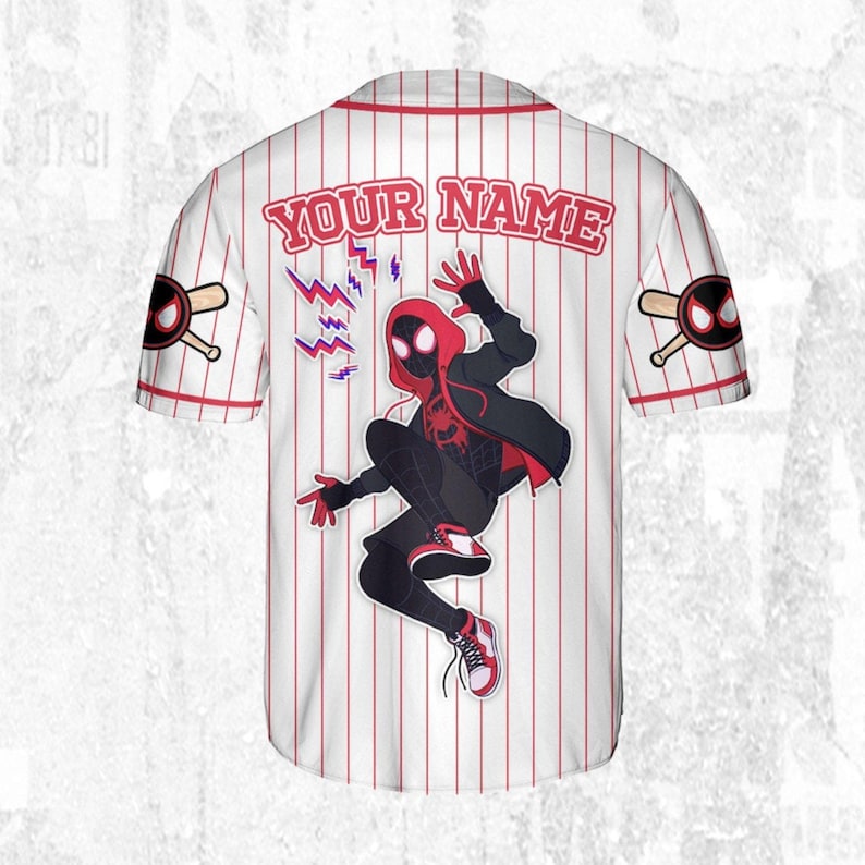 May include: White baseball jersey with red pinstripes, featuring a graphic of a superhero in a dynamic pose. The jersey includes the text "YOUR NAME" across the back, with superhero-themed logos on the sleeves.