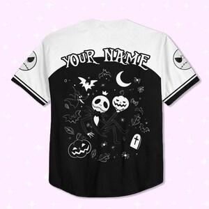 Peut inclure: Un maillot de baseball noir et blanc avec le texte "YOUR NAME" dans le dos. Le maillot pr&eacute;sente une partie inf&eacute;rieure noire avec un motif Jack Skellington tenant une citrouille et une partie sup&eacute;rieure blanche avec une bordure noire. Les manches ont le visage de Jack Skellington.