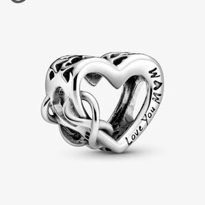 May include: A silver charm with a heart-shaped design. The charm features the words "Love You Mom" and an intertwined knot design. The charm is made of a shiny, reflective metal.