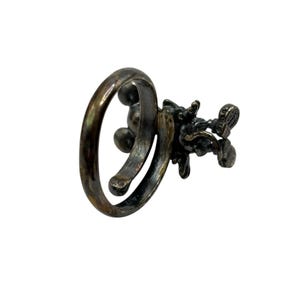 May include: A silver ring featuring a detailed design of a cluster of grapes. The ring is open and adjustable.