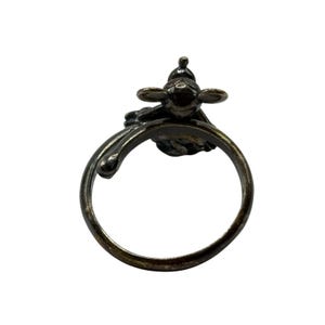 May include: A silver ring featuring a detailed design of a small bird with outstretched wings. The ring is open and has a smooth, rounded band.