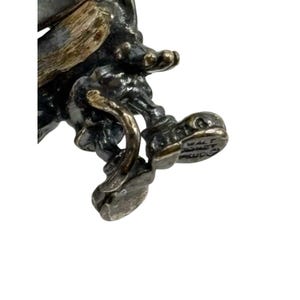 May include: A silver-toned figurine of Mickey Mouse riding a unicycle. The figurine is detailed with a textured finish and has a "Walt Disney Productions" inscription on the bottom.