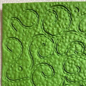 May include: Green textured rubber stamp with a design of swirling lines and dots.