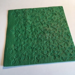 May include: Green silicone baking mat with a raised floral design. The mat is textured and has a repeating pattern of small flowers.