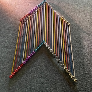 Könnte beinhalten: Eine geometrische Anordnung aus bunten Magnetstäben und silbernen Kugeln. Die Stäbe sind in einer dreieckigen Form angeordnet, wobei jede Seite aus einer Reihe von Kugeln besteht. Die Stäbe sind in verschiedenen Farben, darunter Rot, Gelb, Blau und Lila.