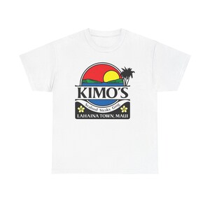 May include: A white short-sleeve t-shirt featuring a graphic logo of a sunset over water with a palm tree. The text reads KIMO'S, Seafood Steaks Grog, and LAHAINA TOWN, MAUI, accompanied by two yellow flower icons on a black background.