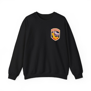 May include: Black crewneck sweatshirt featuring a colorful patch on the upper left chest. The patch includes the text "CAL FIRE" and an image of the state of California, with the words "SINCE 1885". The sweatshirt is a casual garment.