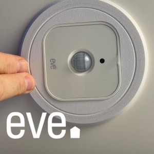 Peut inclure: Un détecteur de mouvement blanc pour maison intelligente avec la marque "eve" imprimée. Le capteur a une lentille arrondie et un petit point noir. L'appareil est monté sur une base circulaire blanche.