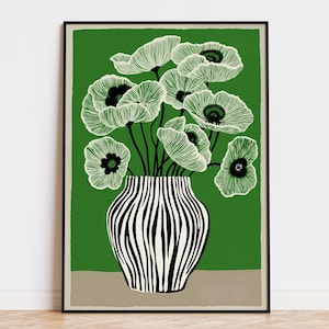 May include: A framed art print featuring a stylized floral arrangement. The artwork showcases light green flowers with black centers in a black and white striped vase against a green backdrop. The vase sits on a tan base.