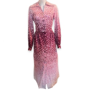 May include: A long-sleeved dress with a collared neckline and button closure. The dress has a pink and burgundy ombre pattern with small white dots.