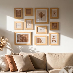 Puede incluir: Un salón con un sofá beige, cojines y una cesta de mimbre. En la pared, cuadros enmarcados con diseños abstractos y la palabra «QUIET». Una lámpara de pie con pantalla beige y flores secas completan la decoración, de estilo minimalista.
