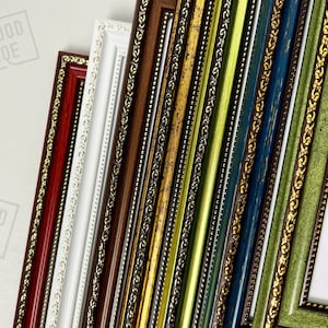 Op de afbeelding: Een verzameling kleurrijke fotolijsten in verschillende tinten, waaronder rood, wit, bruin, goud, groen en blauw. Elke lijst heeft sierlijke gouden details langs de randen, waardoor een decoratieve rand ontstaat.