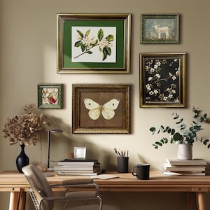May include: A home office setup with a wooden desk displaying framed botanical prints and a butterfly illustration. A black vase with dried flowers, a black mug, and books are on the desk. The wall is painted a neutral beige colour.