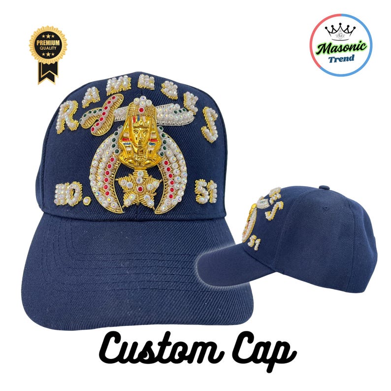 K&ouml;nnte beinhalten: Marineblaue Custom Cap mit goldenen, wei&szlig;en und roten Verzierungen. Die Kappe zeigt den Text "RAMSES" und "51" mit einem zentralen Emblem. Die Worte "Custom Cap" sind in einer Schriftart am unteren Rand geschrieben.