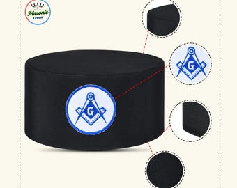 May include: Black cylindrical hat with a blue and white embroidered emblem. The emblem features a compass, a square, and the letter "G" inside a circle. The hat has a flat top and a solid black color. The brand name "Masonic Trend" is in the upper left corner.