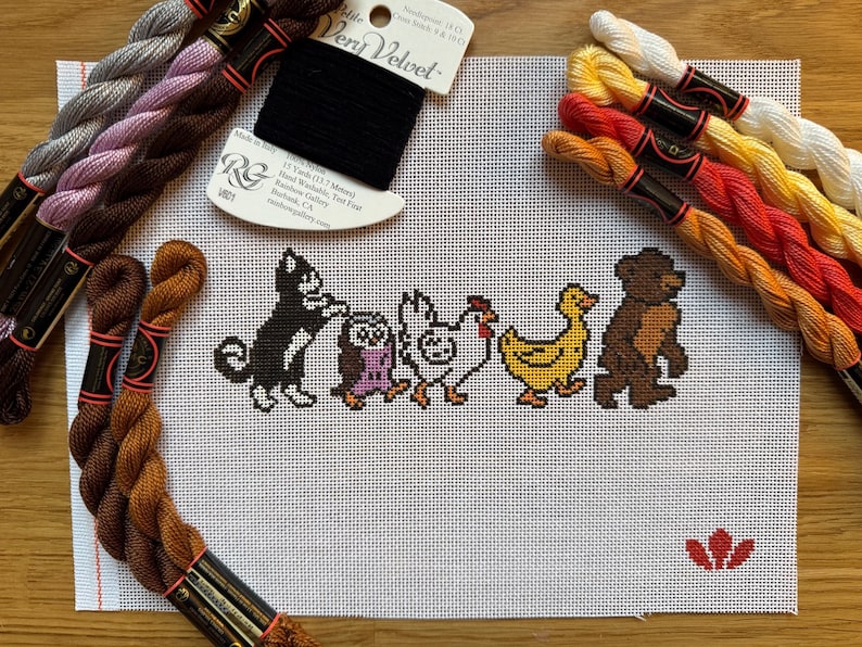 May include: Cross-stitch project featuring a line of cartoon animals: a cat, owl, chicken, duck, and bear. The animals are stitched in black, brown, yellow, and purple on white canvas. Bundles of embroidery floss in various colors surround the canvas.