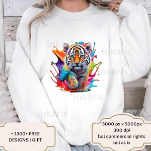 May include: White sweatshirt with a colorful graphic of a tiger cub with paint splatters. The text "1300+ FREE DESIGNS | GIFT" is at the bottom left corner of the image. The text "5000 px x 5000px 300 dpi full commercial rights sell as is" is at the bottom right corner of the image.