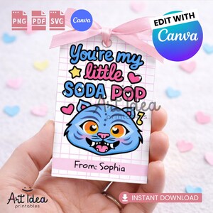 Peut inclure: Une étiquette cadeau rectangulaire avec un ruban rose, représentant une illustration de chat bleu et le texte "You're my little SODA POP". L'étiquette comprend le texte "From: Sophia" et le logo Canva.