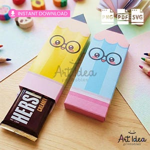 May include: Two pencil-shaped gift boxes, one yellow and one blue, each with a cartoon face and glasses. The yellow box holds a Hershey's Creamy chocolate bar. The boxes are labeled "Art Idea printables" and "Instant Download".