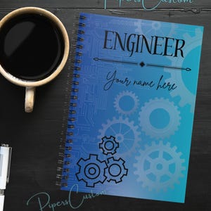 May include: A blue and teal spiral notebook with a circuit board design and the text "Engineer" and "Your name here". The notebook has a black spiral binding and a black gear design.