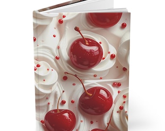 May include: A hardcover journal featuring a whimsical design of cherries and whipped cream. The cover art showcases bright red cherries with green stems atop swirls of white cream, and small red sprinkles.