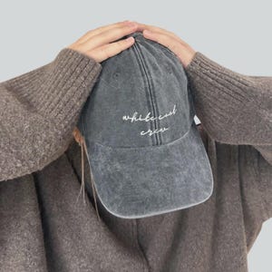 May include: A gray baseball cap with the embroidered text "white coat crew" in white script. The cap has a curved brim and a distressed, vintage look. The cap is made of a soft, durable material.