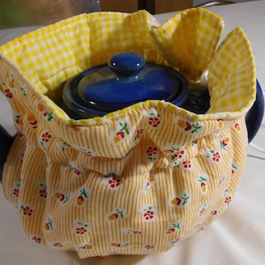 May include: A yellow and white gingham teapot cozy with a blue teapot inside. The cozy has a drawstring closure and is decorated with small red flowers.
