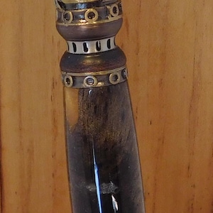 May include: A steampunk-style pen with intricate metal detailing. The pen features a dark brown barrel with a glossy finish, accented by brass-colored gears and decorative elements. The clip has a unique, curved design.