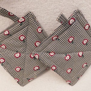 May include: Two quilted pot holders with a black and white checkered pattern and red apple designs. Each pot holder has a loop for hanging. The pot holders are made of fabric and are designed to protect hands from heat.