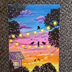 May include: A vibrant painting depicts a sunset scene with birds perched on a string of glowing lights. The sky transitions from blue to pink and orange, with a small house and trees in silhouette.