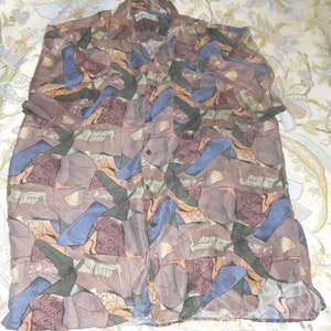 Peut inclure: Une chemise boutonnée à col avec un motif géométrique abstrait en brun, bleu et vert.