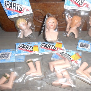 Puede incluir: Una colección de piezas de muñecas de porcelana en bolsas de plástico individuales. Las piezas incluyen cabezas, brazos y piernas. Las bolsas están etiquetadas como "Spare Parts" e incluyen la descripción "Piezas de muñecas de porcelana".