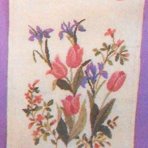 Op de afbeelding: Een bloemenkruissteekontwerp met roze tulpen, paarse irissen en kleine oranje bloemen op een crèmekleurige achtergrond. De tekst "CW 2-3290 C 26 x 106 cm" is zichtbaar. Bovenop zit een rode sticker. Afmetingen: 26 cm x 106 cm.