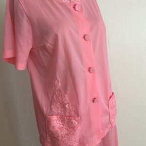 May include: A pink pajama set with lace trim and pockets. The top has a button-up front and short sleeves. The pants have a straight leg.