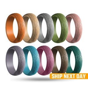May include: A collection of ten silicone rings in various colors, each with a textured wood grain pattern. Colors include orange, tan, gray, green, pink, purple, teal, burgundy, brown, and teal. The rings are displayed against a white background.