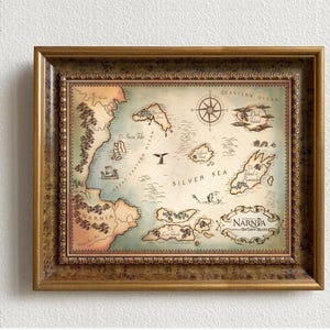 May include: A framed map of the fictional land of Narnia, featuring the text "The Chronicles of Narnia" and "The Lion, the Witch, and the Wardrobe". The map is in a gold frame with a decorative border.
