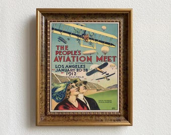 May include: A vintage poster advertising "The People's Aviation Meet", a 3rd International event held in Los Angeles, California, from January 20-28, 1912, at Dominguez Field. The poster features a colorful illustration of airplanes and a blimp.