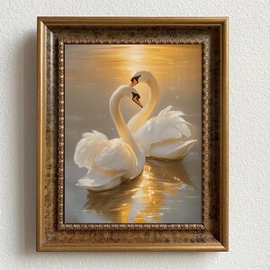 May include: A framed painting depicting two white swans with their necks intertwined, swimming in a golden sunset. The swans are in the foreground of the painting, with a blurred background of water and sky.
