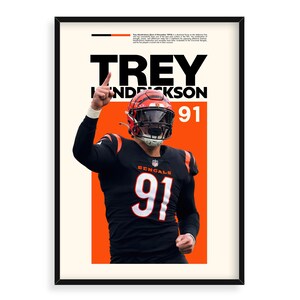 May include: A football player wearing a black jersey with the number 91 and the word "Bengals" on it. He is raising his right arm in the air and has a determined look on his face. The background is orange with the text "Trey Hendrickson 91" in black.